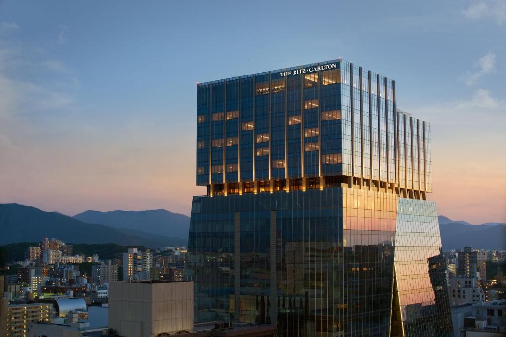 a tall glass building with a city in the background at The Ritz-Carlton Fukuoka in Fukuoka