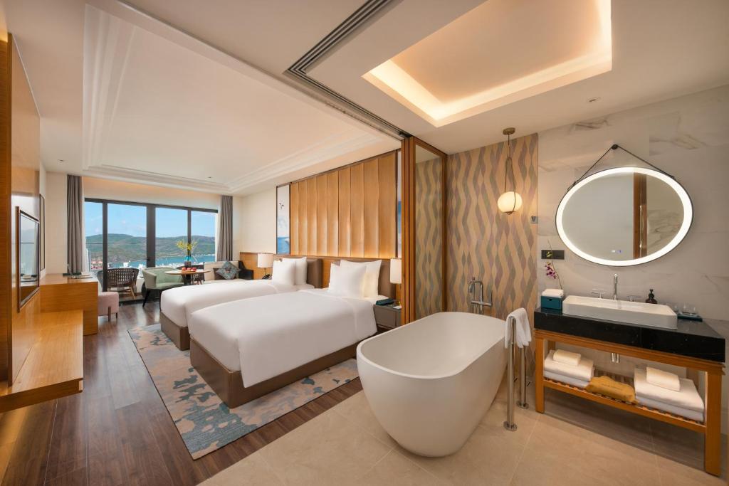 a hotel room with a bed and a tub and a sink at Grand Hyams Hotel - Quy Nhon Beach in Quy Nhon