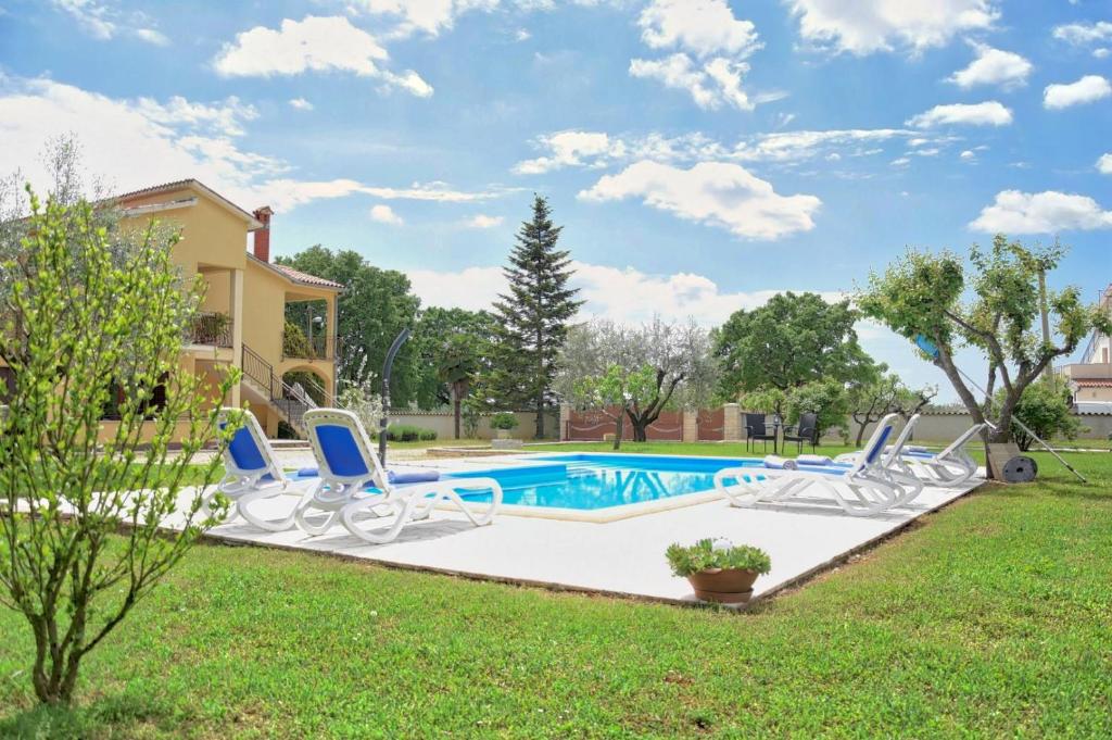 una piscina con sedie a sdraio e una casa di Studio Apartment Petra 3 a Kirmenjak