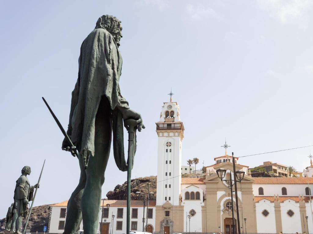 a statue in front of a building with a clock tower at Live Basilica Candelaria Beach & Balcony in Candelaria
