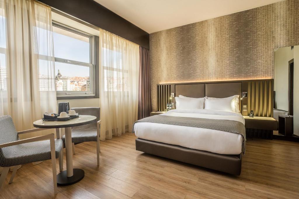 um quarto de hotel com uma cama, uma mesa e uma janela em HF Fenix Lisboa em Lisboa