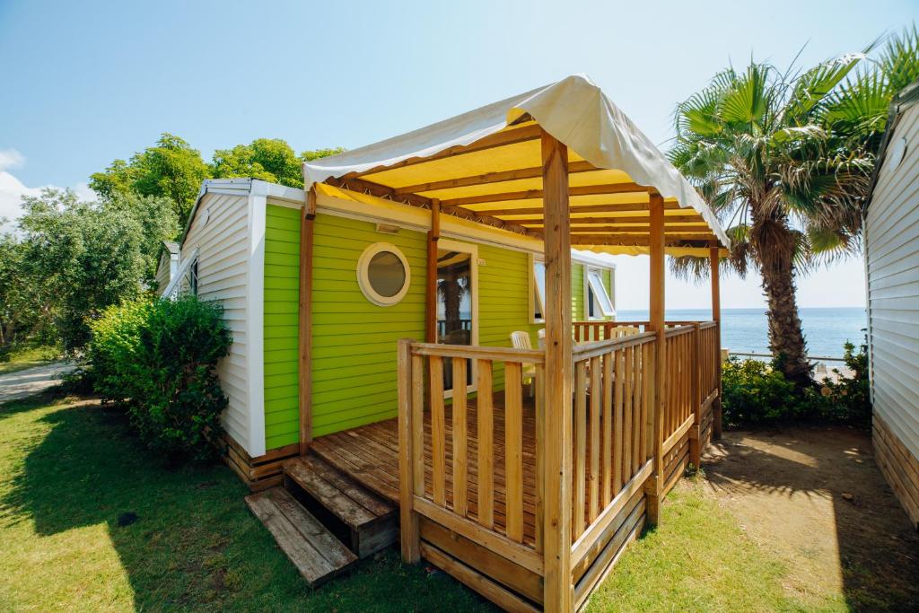 ein grünes und weißes Haus mit einer Terrasse in der Unterkunft Alannia Costa Dorada in Playa de la Almadraba