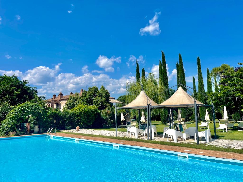 einen Pool mit Stühlen und Sonnenschirmen neben einem Haus in der Unterkunft Casale Baldelli Apartments in Castiglione del Lago