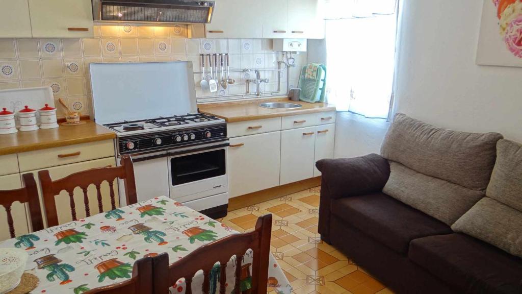 a kitchen with a stove and a living room with a couch at Piso de Laura en primera planta in Lariño