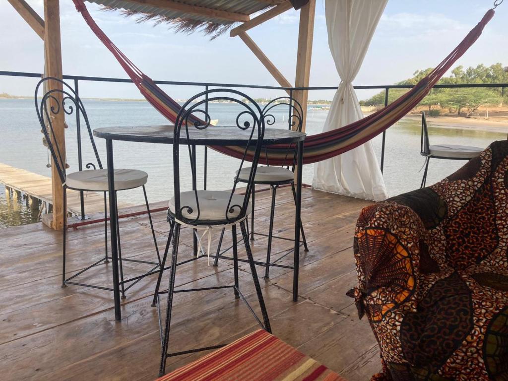 a hammock on a porch with a table and chairs at Maison flottante in Ndangane