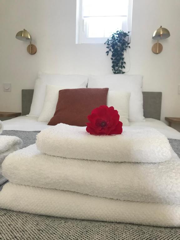 - une pile de serviettes sur un lit avec une fleur rouge au-dessus dans l'établissement - La Vie Douce - Entre Océan & Marais, à Saint-Michel-en-lʼHerm