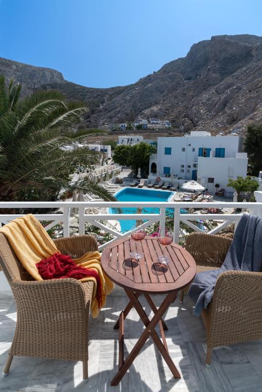 een houten tafel op een patio met stoelen en een zwembad bij Hotel Matina in Kamari