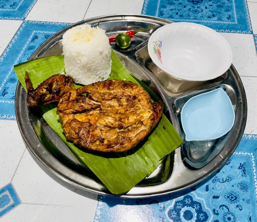 Bossing Inasal في Tubigon: طبق من الطعام مع لحم ورز على طاولة