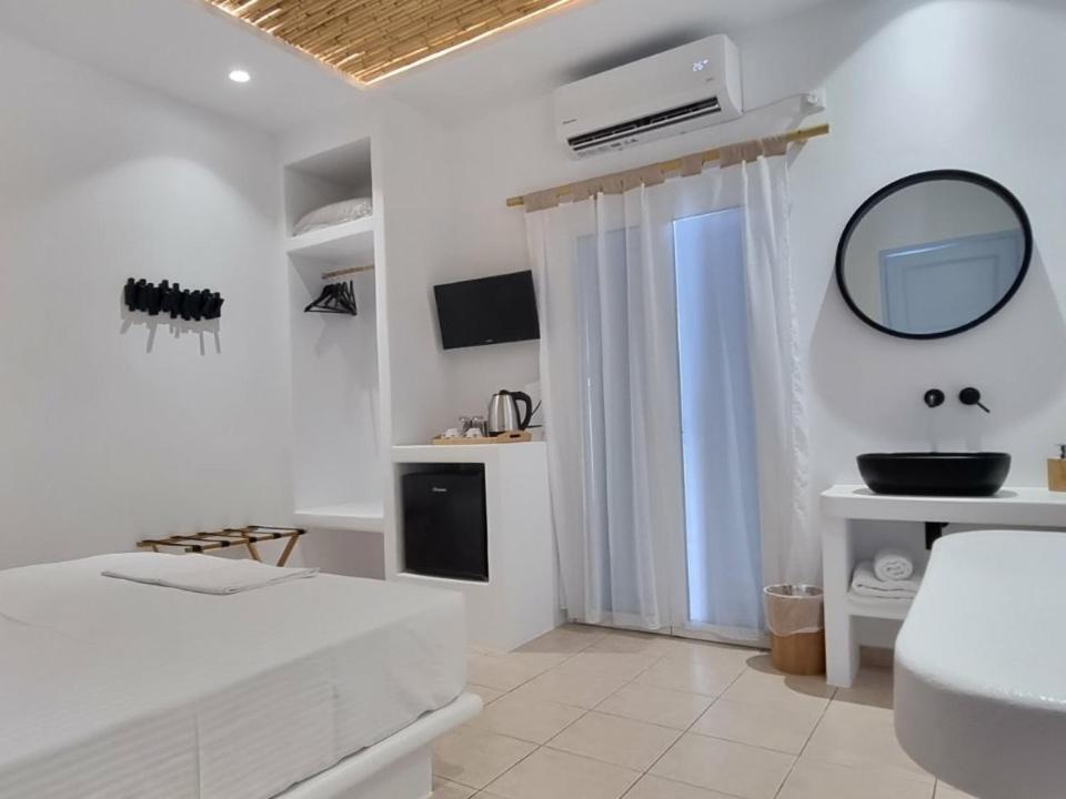 a white bedroom with a bed and a mirror at Ilias Place in Ios Chora