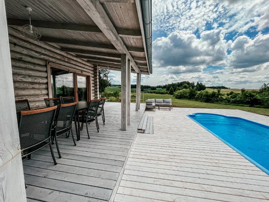 a wooden deck with chairs and a swimming pool at Sielski dom z basenem w Rydzewie in Rydzewo