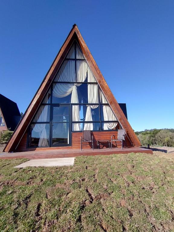 a house with a large window on top of a field at CABANAS CHEIRO DE MATO in Cambara do Sul