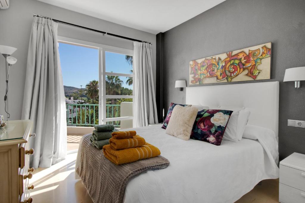 a bedroom with a white bed and a large window at Apartamento en complejo con piscina, pádel y restaurante con vistas al golf en Mijas - Matchroom 83 in Fuengirola