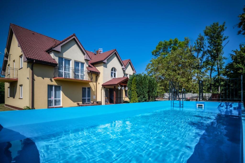 a large swimming pool in front of a house at Pensjonat Malwa z basenem in Niechorze
