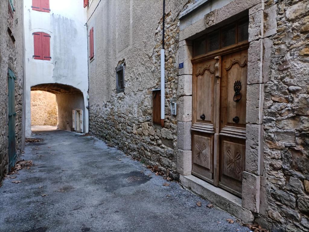 an alley with a stone building and a wooden door at La Jolie Dourbie de Nant in Nant