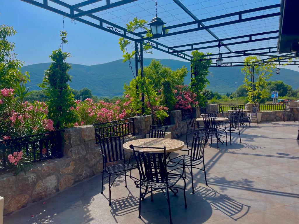 a patio with tables and chairs with mountains in the background at Hotel Opera Jaz in Budva