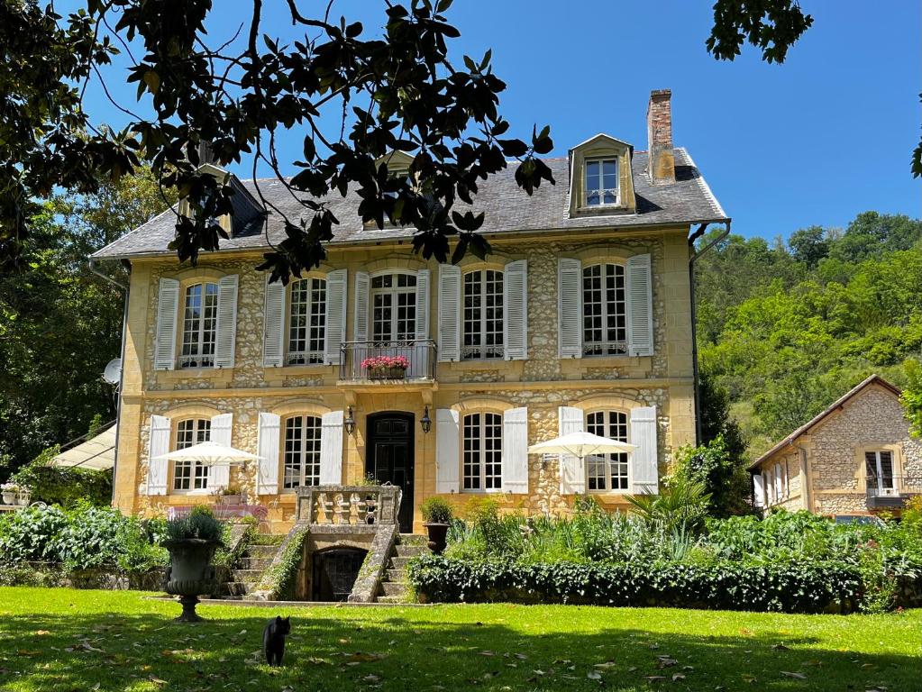 a large yellow house with a porch and a yard at The Coachman’s House in Siorac-en-Périgord