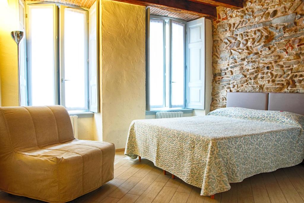 a bedroom with a bed and a chair and windows at B&B Home Sweet Home in Bergamo