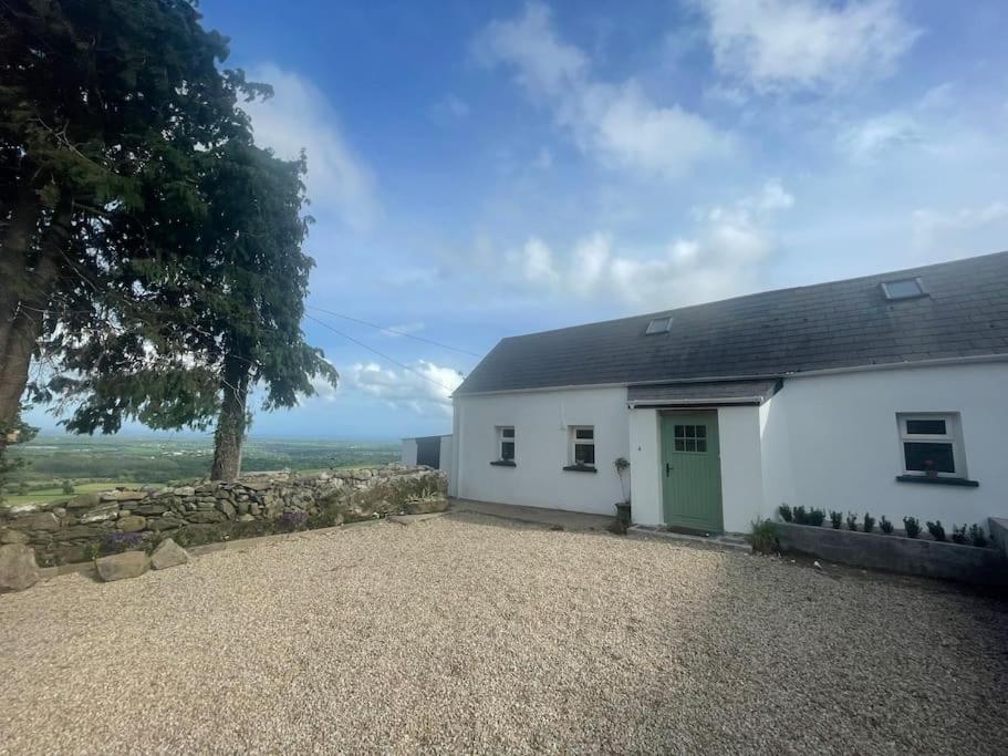 a white house with a green door and a stone wall at Glenogue Farm in Gorey