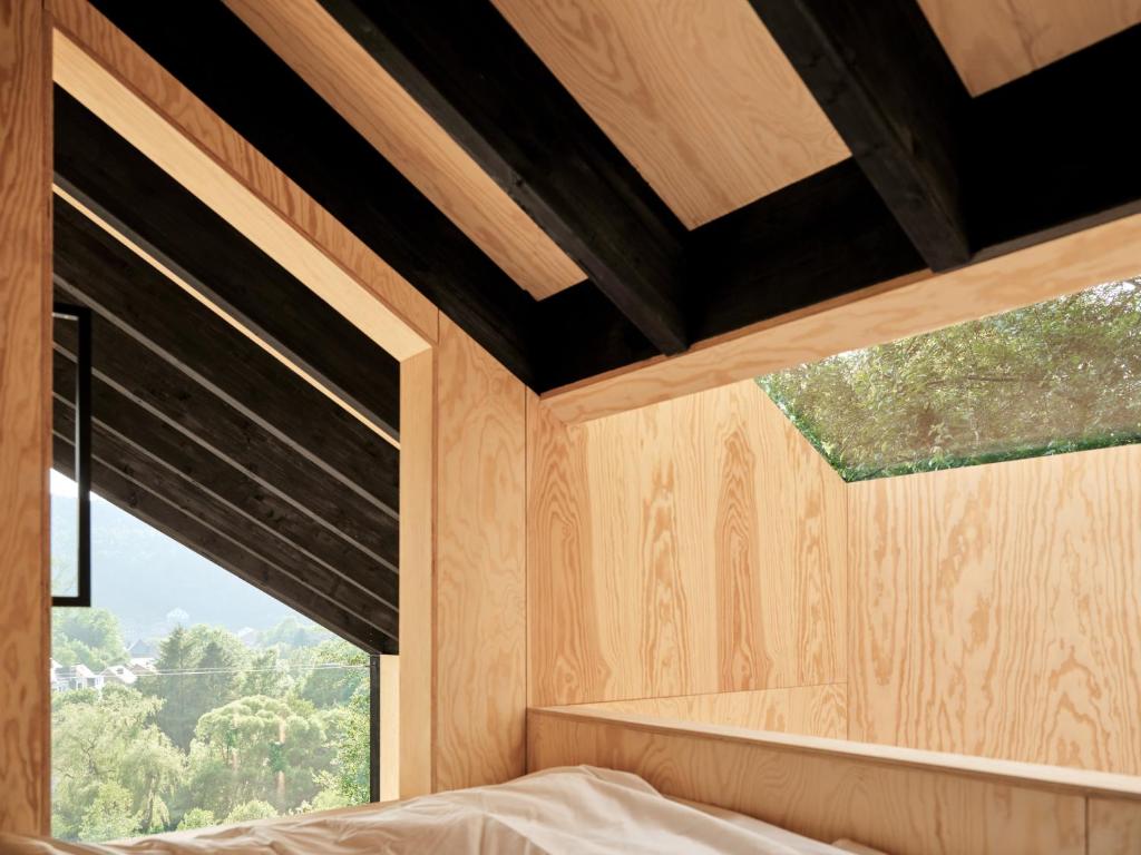 een slaapkamer met houten lambrisering en een raam bij Hutstuf The Beaver & Private Outdoor Spa in La-Roche-en-Ardenne
