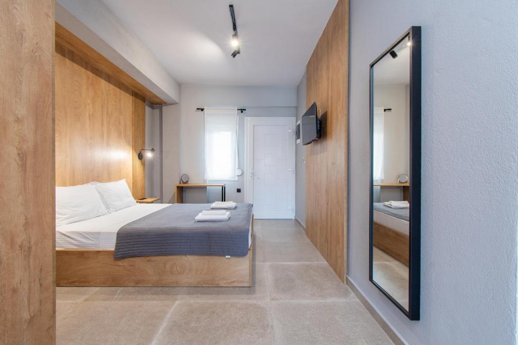 małą sypialnię z łóżkiem i lustrem w obiekcie Unique Aura Luxury Studios w mieście Neos Marmaras