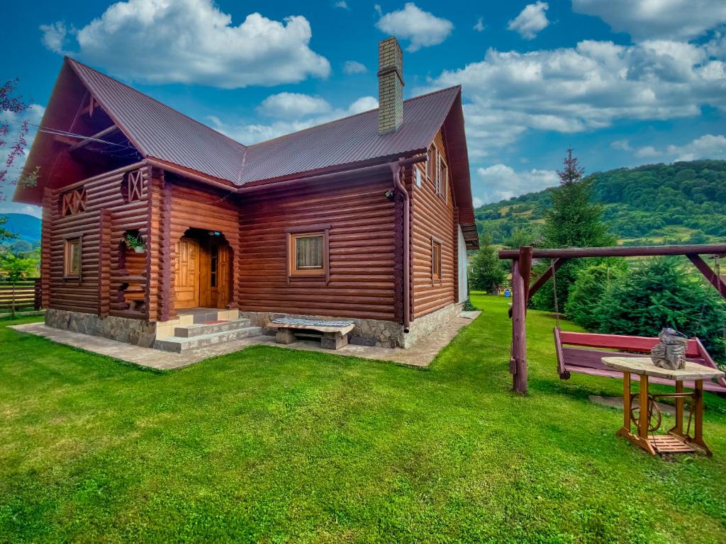 una cabaña de madera con un banco en el patio en Private House Затишок, en Zhdeniievo