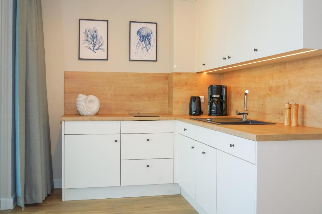 a kitchen with white cabinets and a sink at Appartements "Zum Leuchtturm" Hafen Rankwitz Insel Usedom in Rankwitz