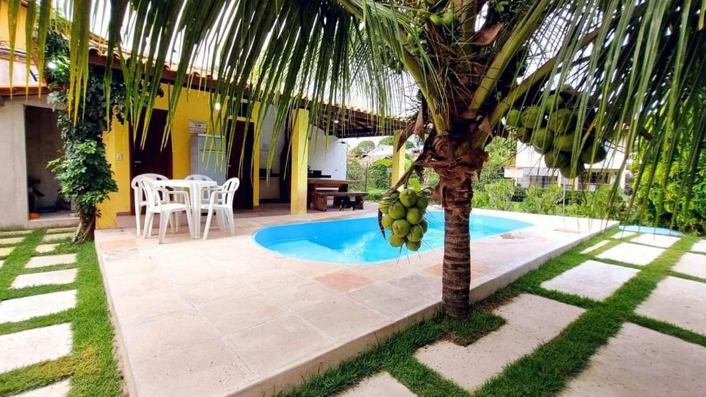 un palmier en face d'une maison avec piscine dans l'établissement Residencial Recanto da Lagoa - Praia de Taperapuan, à Porto Seguro