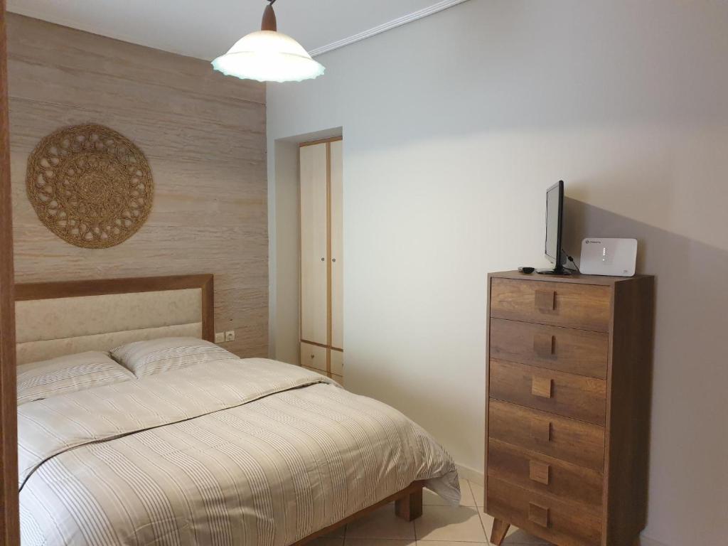 a bedroom with a bed and a dresser with a television at Κεντρικό στούντιο 250m σχεδόν από την παράλια. in Volos