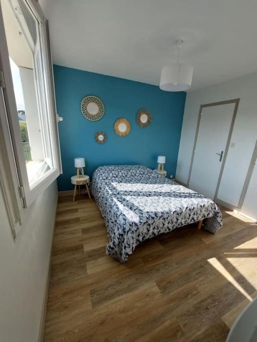 um quarto com uma cama e uma parede azul em 2 pièces à deux pas de la plage. em Fouesnant