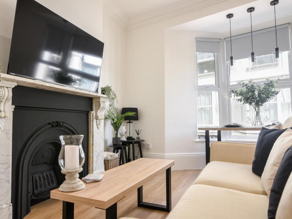 a living room with a fireplace with a tv above it at Fore Street House - Apartment 2 in Seaton