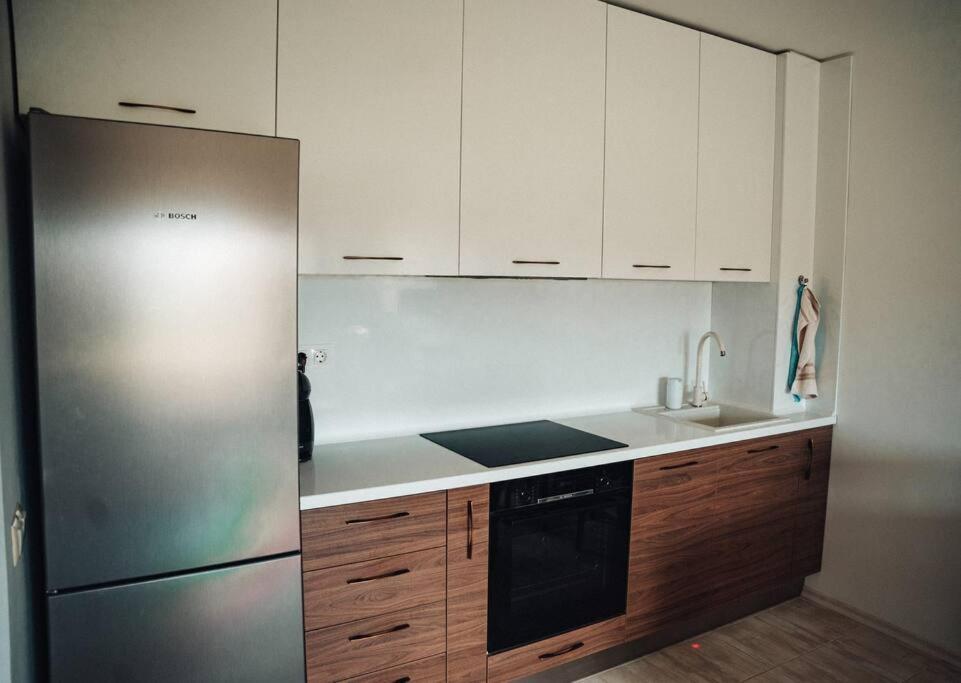 a kitchen with a stainless steel refrigerator and wooden cabinets at Lovely apartment near Kavatsi in Sozopol