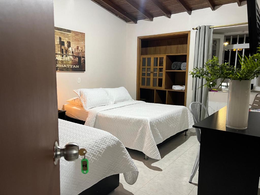 una habitación con 2 camas y una puerta con una habitación con 2 camas en New Memphis Hostal, en Medellín