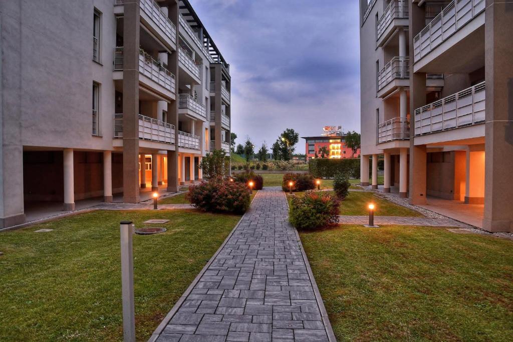 a walkway between two buildings with lights in the grass at Bloom Apartment in Pero