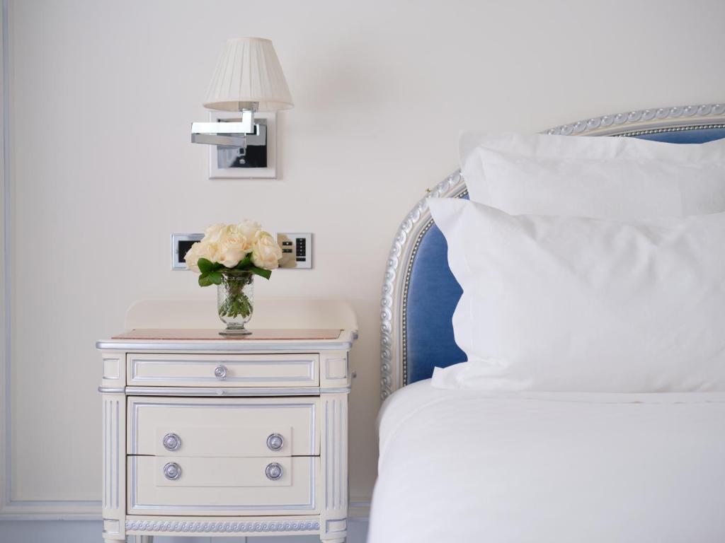 a white nightstand with a vase of flowers on top of a bed at The Ritz London in London