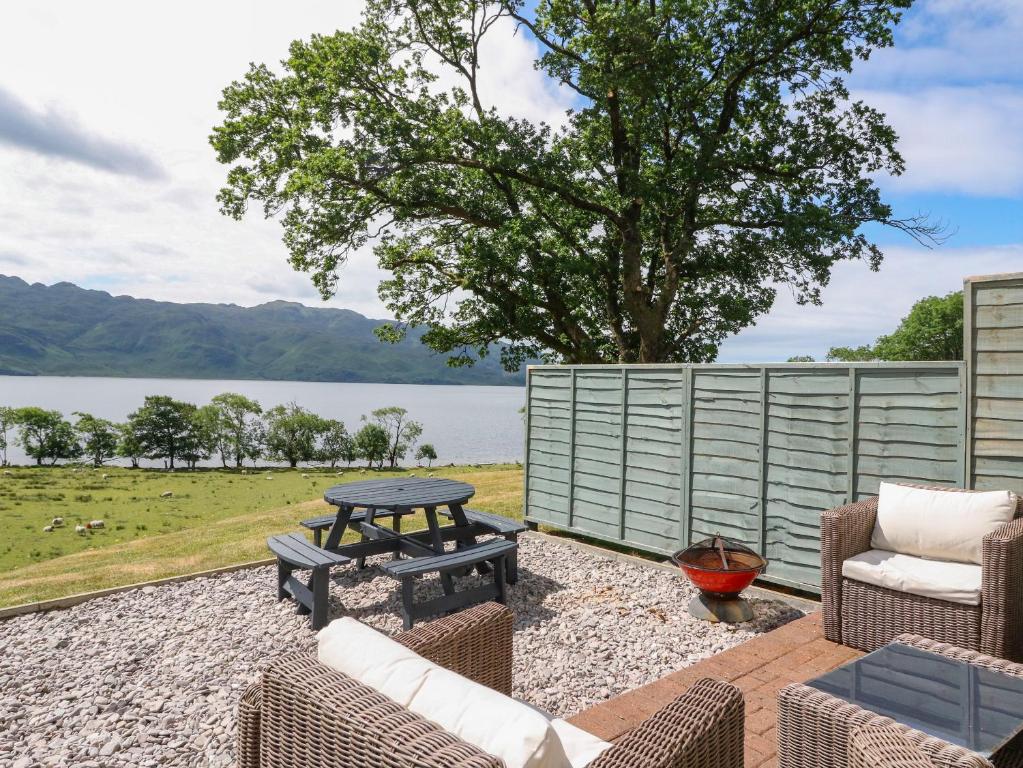 a patio with a table and chairs and a lake at Croft House in Mallaig