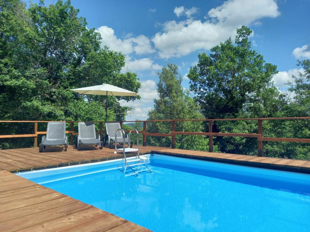 a swimming pool with two chairs and an umbrella at Valle Dame in Cortona