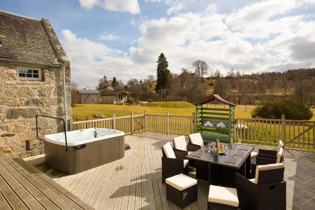 a deck with a bath tub and a table and chairs at The Maltings - lodge with hot tub in Nethy Bridge