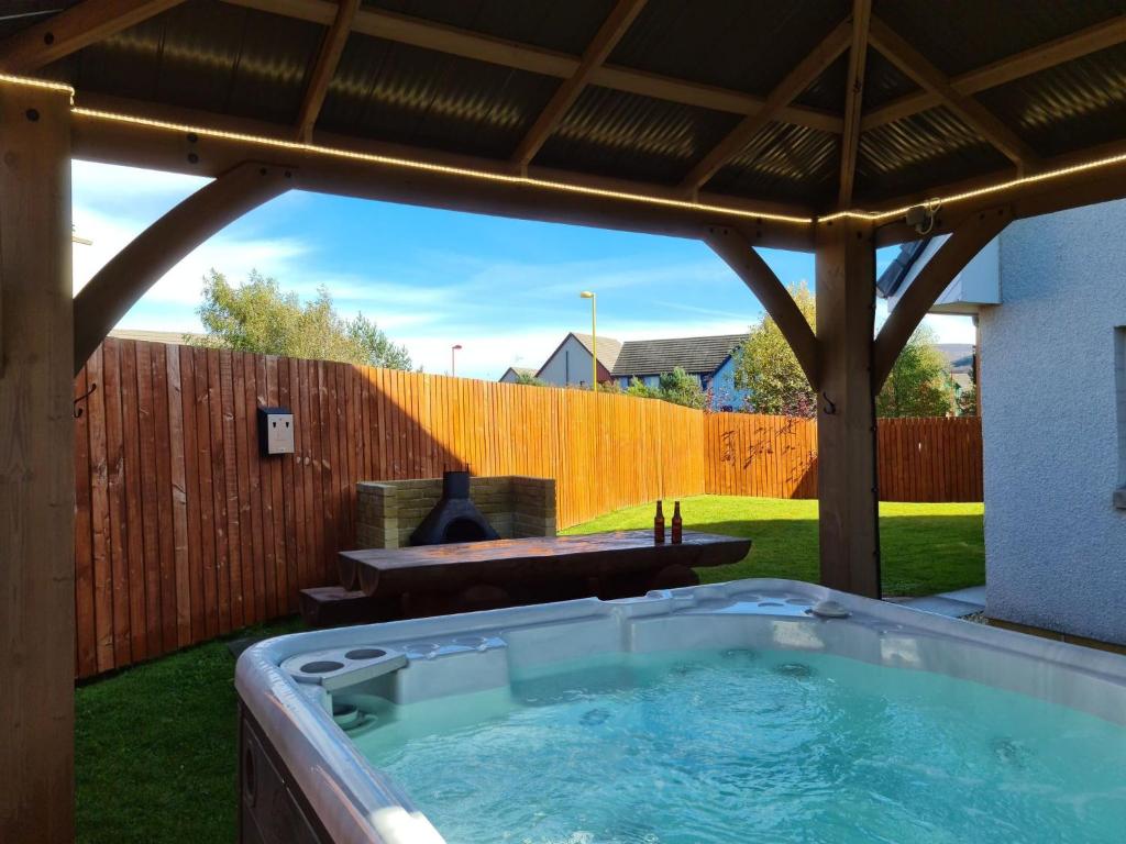 una bañera de hidromasaje en un patio trasero con una valla de madera en Eagle Lodge - Aviemore Lodges en Aviemore