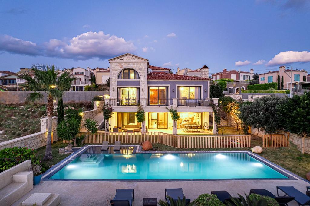 a house with a swimming pool in front of a house at VillaSunset with Magnificent Sea View in Çeşme
