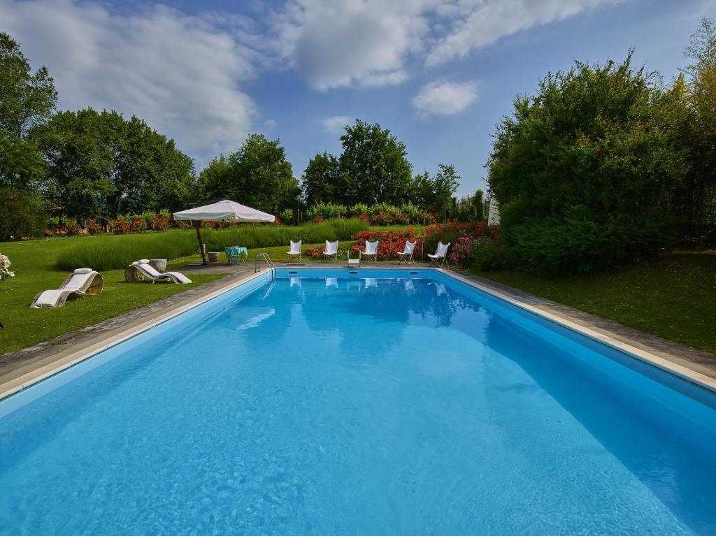 a large blue swimming pool in a yard with chairs at Villa della Corte - Homelike Villas in Erbusco