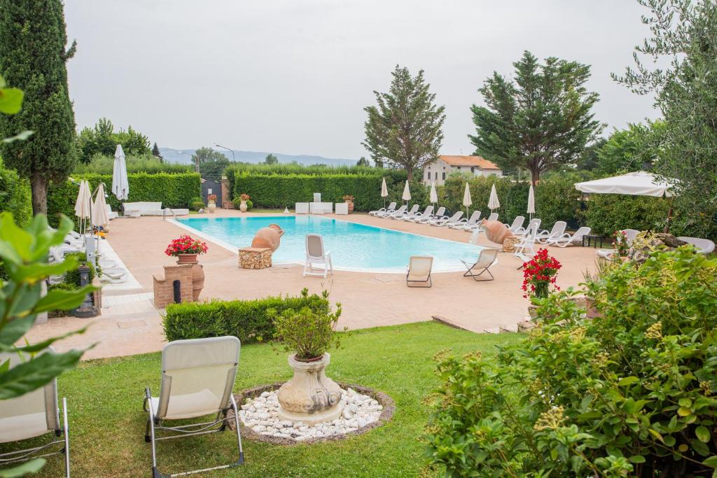 einen Pool mit Stühlen und einen Garten mit Pool in der Unterkunft Hotel Villa Verde in Rivotorto