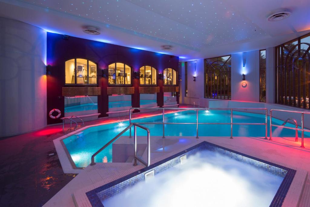 a swimming pool in a building with a tub at Crowne Plaza Gerrards Cross, an IHG Hotel in Beaconsfield