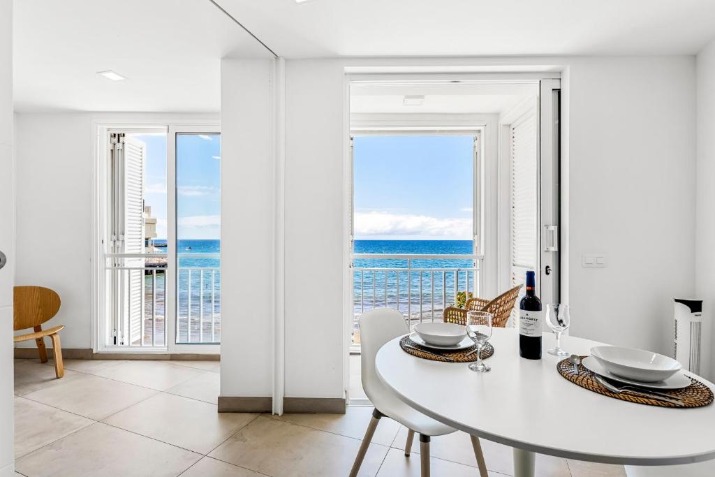 uma sala de jantar branca com uma mesa e vista para o oceano em MEDANO4YOU Charly Blau em El Médano