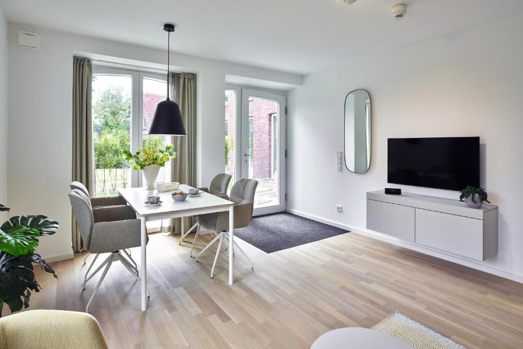 un salon blanc avec une table et une télévision dans l'établissement Lüttjeod Apartmentvilla Lüttjeod Apartmentvilla 03, à Langeoog