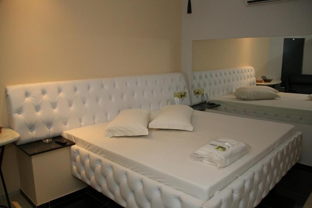 uma cama branca com duas almofadas em cima em SAFIRA MOTEL II em Fernandópolis