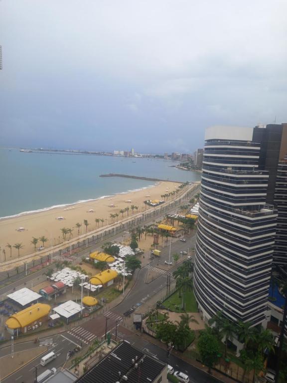 un edificio alto junto a una playa y un edificio en Hotel Flat Atlântico, Apartamento Com 02 Quartos, en Fortaleza