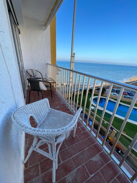 a wicker chair sitting on a balcony overlooking the ocean at RIBERA PLAYA ALHAMAR in Sitio de Calahonda