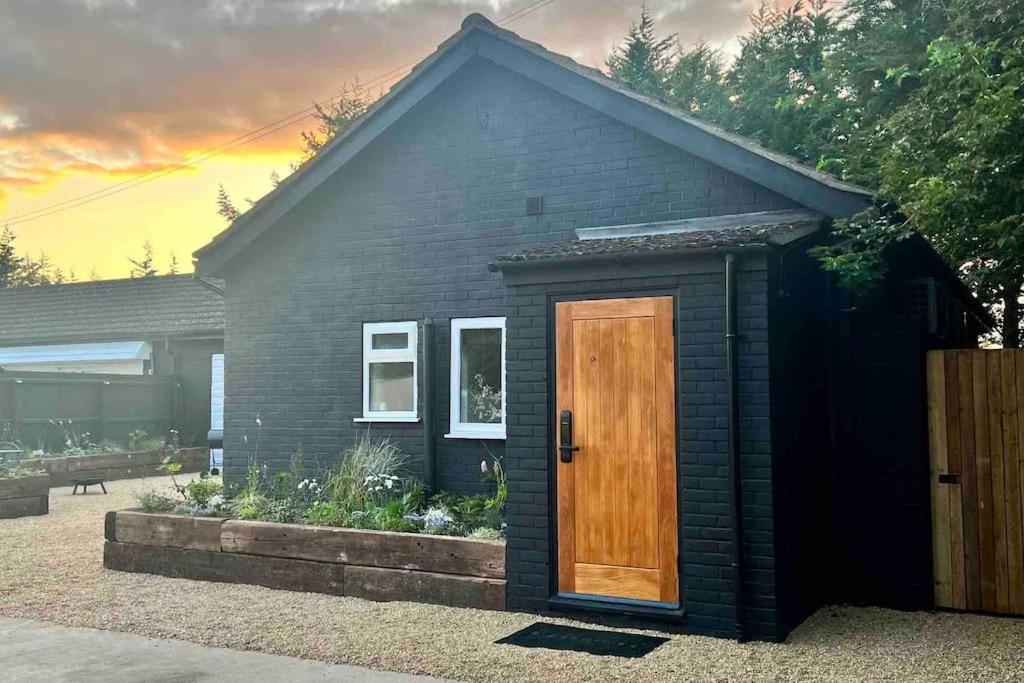 una pequeña casa negra con puerta de madera en The Saddle Inn, Snetterton Circuit, en Norwich