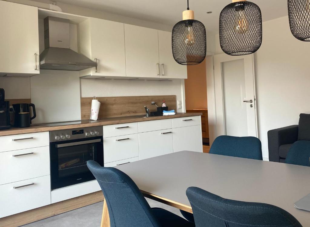 a kitchen with white cabinets and a table and chairs at Ferienwohnung Nordwind - Haus Seeschwalbe in Wangerland