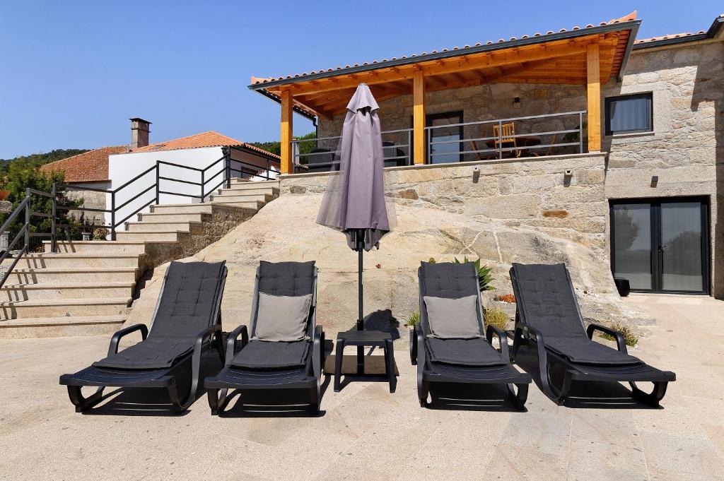 a group of lawn chairs and an umbrella at Casa da Lage in Castelo do Neiva